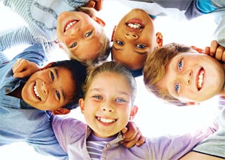 Looking up at a group of happy children in a circle with their heads together.
